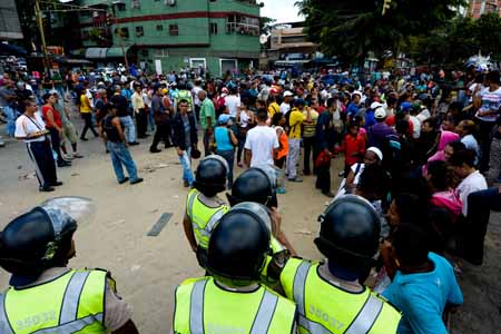 Efectivos de la Policía Nacional Bolivariana resguardan a la gente que protestó por la falta de comida este sábado en CatiaAFP / Federico Parra