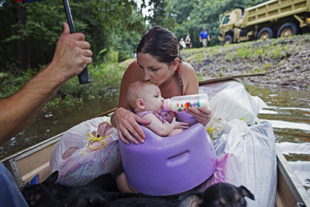 Danielle Blount besa a su hija de tres meses, Ember, mientras le da su biberón y esperan ambas a ser rescatadas por la Guardia Nacional cerca de Walker, Louisiana.
MAX BECHERER / AP