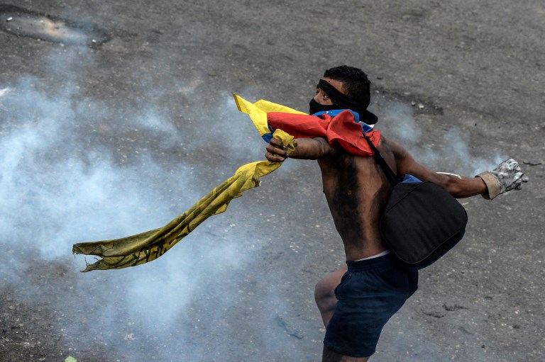 An opposition activist clashes with the police at the Francisco de Miranda air force base during a demonstration against the government of Venezuelan President Nicolas Maduro in Caracas on June 24, 2017, near the place where a young man was shot dead by police during an anti-government rally two days ago. A political and economic crisis in the oil-producing country has spawned often violent demonstrations by protesters demanding Maduro's resignation and new elections. The unrest has left 75 people dead since April 1. / AFP PHOTO / FEDERICO PARRA