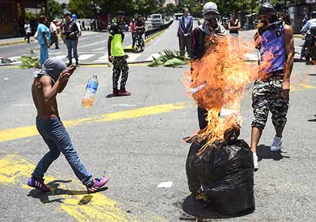 Anti-government activists demonstrate against Venezuelan President Nicolas Maduro at a barricade set up on a road in Caracas on August 8, 2017.Recent demonstrations in Venezuela have stemmed from anger over the installation of an all-powerful Constituent Assembly that many see as a power grab by the unpopular President Maduro. The dire economic situation also has stirred deep bitterness as people struggle with skyrocketing inflation and shortages of food and medicine. / AFP PHOTO / Ronaldo SCHEMIDT