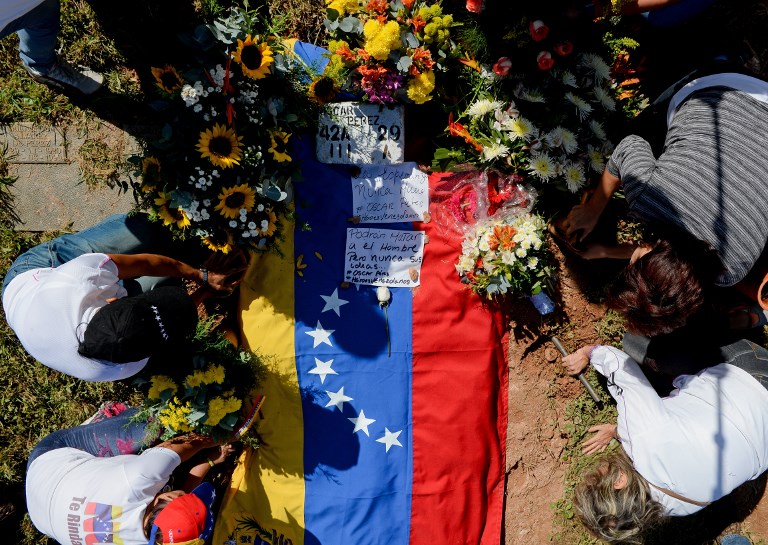 Former elite police officer Oscar Perez's supporters place flowers next to his gravesite at a cemetery in Caracas on January 21, 2018.
Perez's body was burried by the government early in the morning on January 21 against his family will. He was Venezuela's most wanted man since June when he flew a stolen police helicopter over Caracas dropping grenades on the Supreme Court and opening fire on the Interior Ministry, had gone on social media while the operation was under way on January 16 to say he and his group wanted to surrender but were under unrelenting sniper fire. That has raised questions about the government's account that the seven dissidents killed had opened fire on police who had gone to arrest them. / AFP PHOTO / Federico PARRA