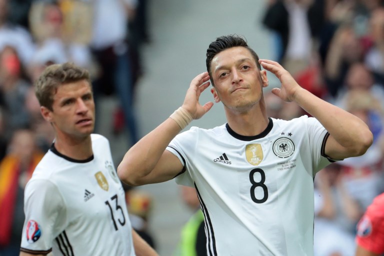 (FILES) In this file photo taken on June 26, 2016, Germany's midfielder Mesut Oezil (R) reacts during the Euro 2016 round of 16 football match between Germany and Slovakia at the Pierre-Mauroy stadium in Villeneuve-d'Ascq near Lille on June 26, 2016.Mesut Ozil's decision to quit playing for the German national football team Die Mannschaft unleashed on July 23, 2018 a racism storm in Germany, but earned the applause of Ankara with a Turkish minister hailing "a goal against the virus of fascism". / AFP PHOTO / KENZO TRIBOUILLARD