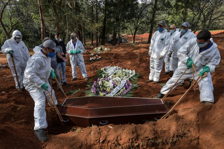 Varios empleados entierran el ataúd de un fallecido por coronavirus en el cementerio brasileño de Vila Formosa, a las afueras de Sao Paulo