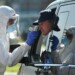 Un trabajador sanitario con indumentaria protectora toma una muestra de mucosa a un hombre en su automóvil para realizar una prueba de detección del coronavirus, este jueves 30 de julio de 2020 en un área de servicio en Alemania