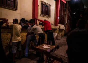 Agentes policiales requisan a un grupo de hombres que jugaban dominó en la calle, en violación de las medidas de cuarentena