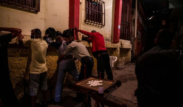 Agentes policiales requisan a un grupo de hombres que jugaban dominó en la calle, en violación de las medidas de cuarentena