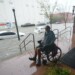 Un hombre en silla de ruedas observa desde una zona alta una calle inundada en el centro de Pensacola, Florida