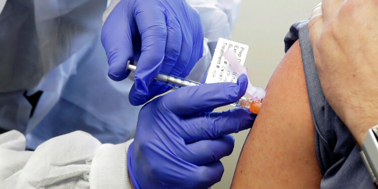 Neal Browning receives a shot in the first-stage safety study clinical trial of a potential vaccine for COVID-19, the disease caused by the new coronavirus, Monday, March 16, 2020, at the Kaiser Permanente Washington Health Research Institute in Seattle. Browning is the second patient to receive the shot in the study. (AP Photo/Ted S. Warren)