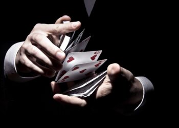 A magician shuffling the cards in a cool way under the spotlight