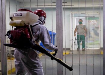 AME1046. CARACAS (VENEZUELA), 28/08/2020.- Fotografía fechada el 6 de abril de 2020 donde se observa a un trabajador público en una jornada de desinfección dentro de un Centro de Diagnostico Integral (CDI) a modo preventivo por el COVID-19 en Caracas (Venezuela). La incertidumbre de Venezuela en casi todos los aspectos de su acontecer diario está servida desde hace años, pero la COVID-19 superó cualquier expectativa. Datos dudosos, números que no cuadran, contradicciones en cifras oficiales, escasez de medicinas y hospitales colapsados. El caos se hizo país. EFE/Rayner Peña