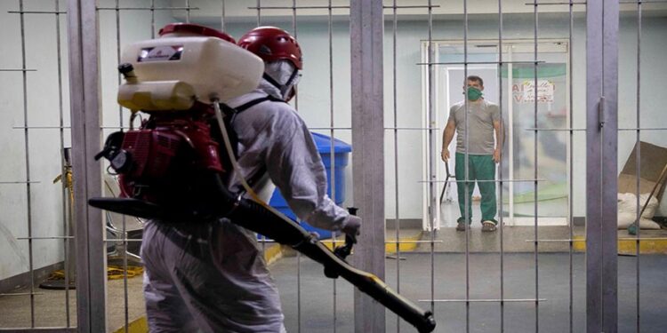 AME1046. CARACAS (VENEZUELA), 28/08/2020.- Fotografía fechada el 6 de abril de 2020 donde se observa a un trabajador público en una jornada de desinfección dentro de un Centro de Diagnostico Integral (CDI) a modo preventivo por el COVID-19 en Caracas (Venezuela). La incertidumbre de Venezuela en casi todos los aspectos de su acontecer diario está servida desde hace años, pero la COVID-19 superó cualquier expectativa. Datos dudosos, números que no cuadran, contradicciones en cifras oficiales, escasez de medicinas y hospitales colapsados. El caos se hizo país. EFE/Rayner Peña