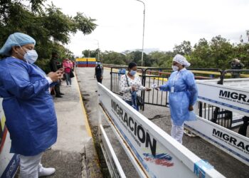 A Colombian health worker takes the temperature of a Venezuelan woman at the Simon Bolivar international bridge in Cucuta, on the Colombian border with Venezuela, on March 13, 2021. (Photo by Schneyder MENDOZA / AFP)