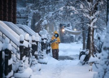 A man shovels snow on a street in the Brooklyn borough of New York during the first snow storm of the season on January 7, 2022. (Photo by Ed JONES / AFP)