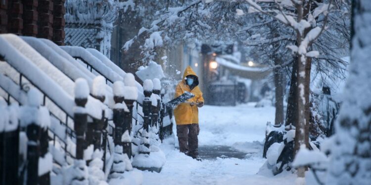 A man shovels snow on a street in the Brooklyn borough of New York during the first snow storm of the season on January 7, 2022. (Photo by Ed JONES / AFP)