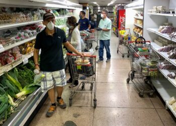 A group of people reviews product prices in a supermarket in Caracas, Venezuela, 27 April 2020. Government of Nicolas Maduro signed on Monday a price list of 27 basic consumer products that will not be known until Tuesday, when Venezuela will officially revert to this type of controls that in the past sparked shortages and now return in the midst of a greater poverty. Vice President of the Economic Area Tareck el Aissami said that the Executive had agreed "fair and solidary prices" after several meetings with producers and distributors that ended, he said, "happily." The signing of these agreements, which was partially broadcast by the state channel VTV, did not include the dissemination of any of the new tariffs or the products that will be the subject of these regulations, although government officials have made it clear that these are items basic or mass consumption. EFE / Miguel Gutierrez