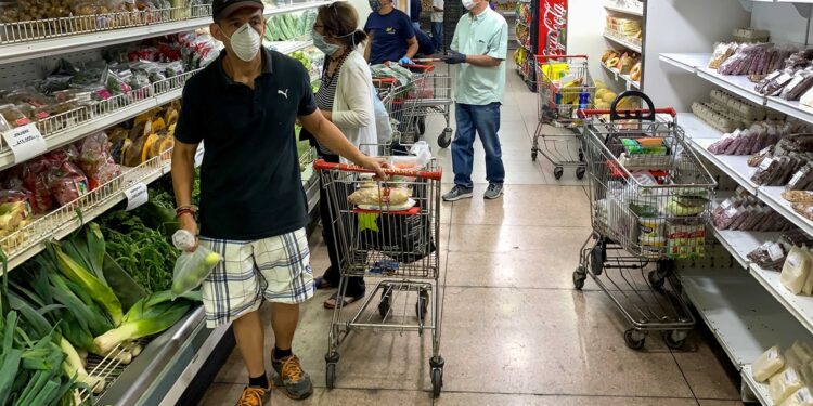 A group of people reviews product prices in a supermarket in Caracas, Venezuela, 27 April 2020. Government of Nicolas Maduro signed on Monday a price list of 27 basic consumer products that will not be known until Tuesday, when Venezuela will officially revert to this type of controls that in the past sparked shortages and now return in the midst of a greater poverty. Vice President of the Economic Area Tareck el Aissami said that the Executive had agreed "fair and solidary prices" after several meetings with producers and distributors that ended, he said, "happily." The signing of these agreements, which was partially broadcast by the state channel VTV, did not include the dissemination of any of the new tariffs or the products that will be the subject of these regulations, although government officials have made it clear that these are items basic or mass consumption. EFE / Miguel Gutierrez