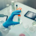 Scientist hand showing vial with vaccine in the laboratory. Selective focus on vial in foreground