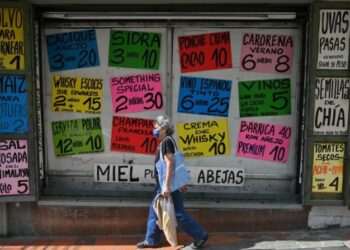 Locals walk past a supermarket displaying signs with prices of products in US dollars, in Caracas, on Arpil 1, 2022. (Photo by Federico PARRA / AFP) (Photo by FEDERICO PARRA/AFP via Getty Images)