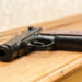 Black pistol on a light wooden background