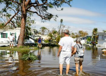 People walk on a flooded street at a trailer park following Hurricane Ian in Fort Myers, Florida, US, on Thursday, Sept. 29, 2022. Ian, now a hurricane again, is threatening to carve a new path of destruction through South Carolina Friday when it roars ashore north of Charleston. Photographer: Eva Marie Uzcategui/Bloomberg