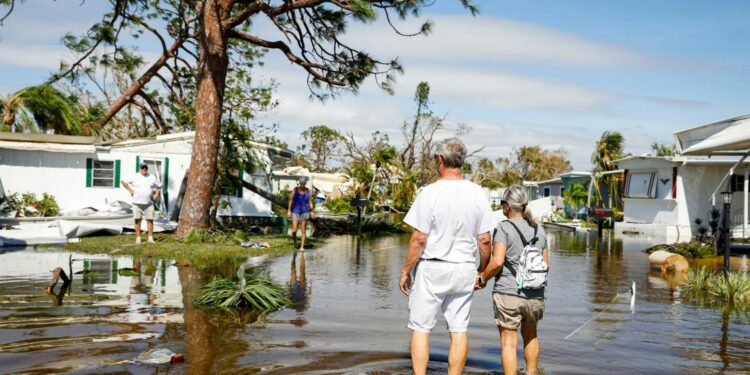 People walk on a flooded street at a trailer park following Hurricane Ian in Fort Myers, Florida, US, on Thursday, Sept. 29, 2022. Ian, now a hurricane again, is threatening to carve a new path of destruction through South Carolina Friday when it roars ashore north of Charleston. Photographer: Eva Marie Uzcategui/Bloomberg
