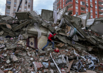 A man walks among rubble as he searches for people in a destroyed building in Adana, Turkey, Monday, Feb. 6, 2023. A powerful quake has knocked down multiple buildings in southeast Turkey and Syria and many casualties are feared. (AP Photo/Khalil Hamra)