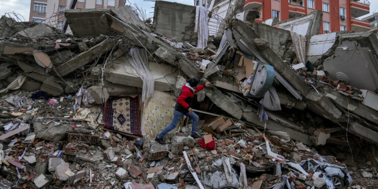 A man walks among rubble as he searches for people in a destroyed building in Adana, Turkey, Monday, Feb. 6, 2023. A powerful quake has knocked down multiple buildings in southeast Turkey and Syria and many casualties are feared. (AP Photo/Khalil Hamra)