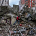 A man walks among rubble as he searches for people in a destroyed building in Adana, Turkey, Monday, Feb. 6, 2023. A powerful quake has knocked down multiple buildings in southeast Turkey and Syria and many casualties are feared. (AP Photo/Khalil Hamra)