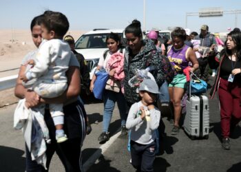 (FILES) Migrants of different nationalities are escorted by Peruvian police officers to a migration office in Tacna, in the Peru-Chile border on April 28, 2023. - Chile confirmed that a first repatriation flight will depart on May 7 for hundreds of Venezuelan migrants stranded on the border with Peru who have been seeking to return to their country of origin for weeks, Chilean Foreign Minister Alberto van Klaveren said on May 4. (Photo by ALDAIR MEJIA / AFP)