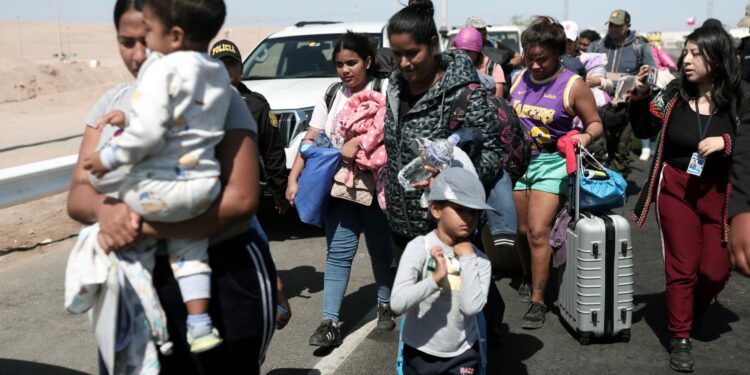 (FILES) Migrants of different nationalities are escorted by Peruvian police officers to a migration office in Tacna, in the Peru-Chile border on April 28, 2023. - Chile confirmed that a first repatriation flight will depart on May 7 for hundreds of Venezuelan migrants stranded on the border with Peru who have been seeking to return to their country of origin for weeks, Chilean Foreign Minister Alberto van Klaveren said on May 4. (Photo by ALDAIR MEJIA / AFP)