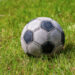 Close-up of an old leather soccer ball on green grass, football sport concept